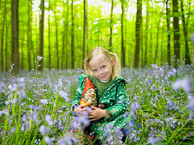 在树林里有个女孩在花园和侏儒拥抱图片