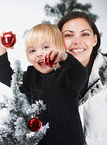 母亲和儿子在装饰一棵圣诞树图片
