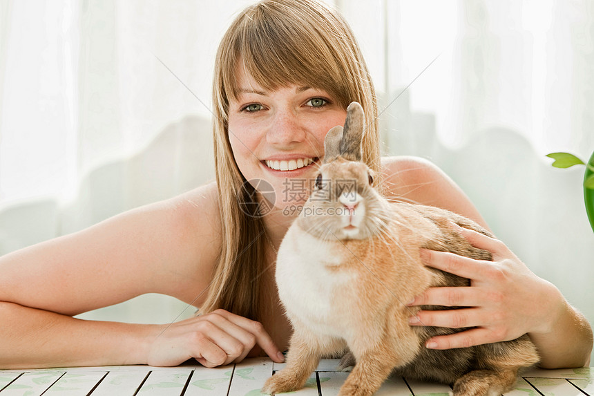 年轻的女人和一只宠物兔子在院子里图片