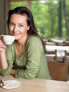 在室内桌子旁拿着杯子的女人图片