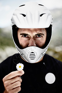 戴着摩托车头盔的男人抱着雏菊图片