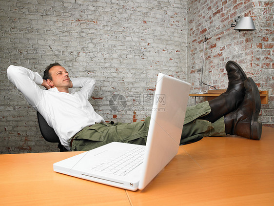 双脚翘在办公桌上休息的商务人士图片