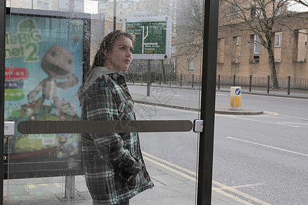 在雨中公共汽车站候车的女性图片