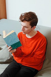在沙发上看书的红衣男子图片