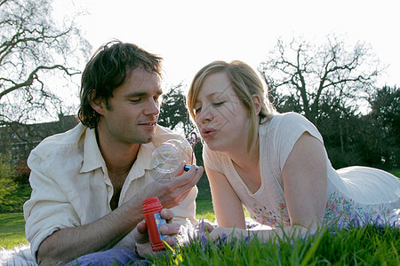 一对夫妇在公园的草地上吹泡泡图片