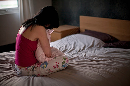 心烦意乱的女人把枕头抱在床上图片