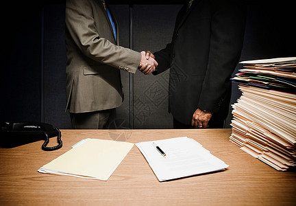 两个商人在办公桌上握手背景图片