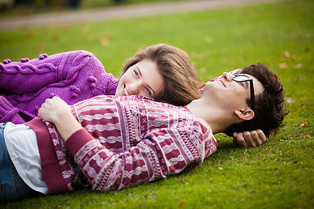 一对年轻夫妇躺在公园的草地上图片