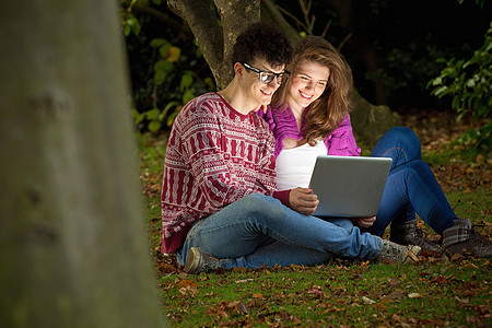 年轻夫妇在公园里用笔记本电脑图片