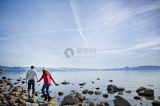 一对夫妇在湖边的岩石上行走图片
