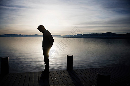 人思考日落时分站在码头上的人背景