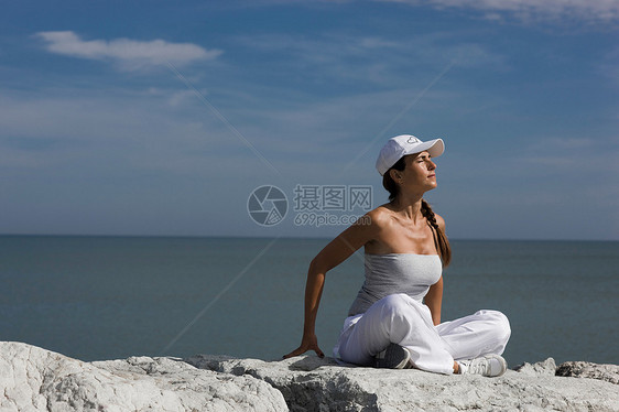 坐在海边岩石上的女人图片