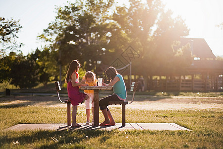3个女孩坐在公园里画画图片