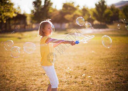玩泡泡在公园里泡大泡泡的小女孩背景
