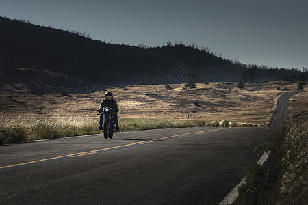 骑在公路上的中年男性摩托车手高清图片