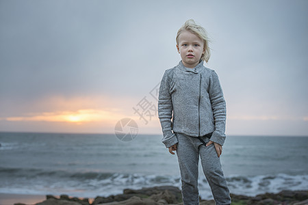 美国加利福尼亚州卡默尔，日落时微风习习的海岸上男孩的肖像图片