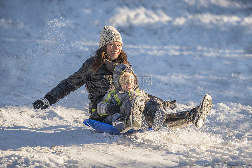 微笑的母子在雪中滑下的照片图片
