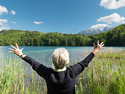 老妇人站在湖边，后视图图片