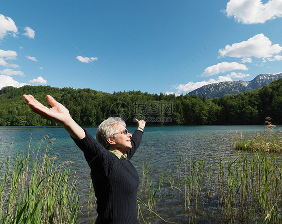 老妇人站在湖边，侧视图图片
