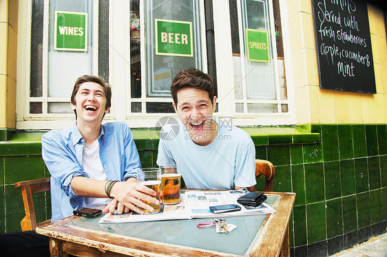 微笑的男人在咖啡馆喝啤酒图片