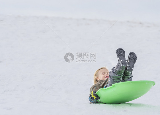 在雪中玩托博根的男孩图片