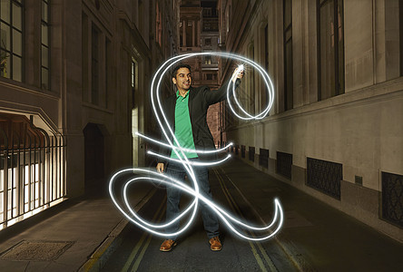 商人在晚上城市街道上画着发光的英镑标志图片