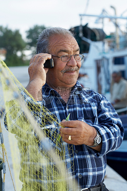 成熟的渔夫在打手机的时候固定渔网图片