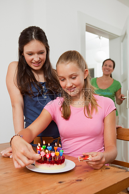 女孩在生日蛋糕上点蜡烛图片