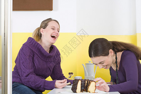 两个年轻女人坐在桌子大笑着图片