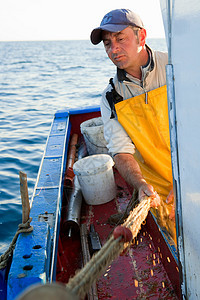 渔人在船上卷起渔网图片