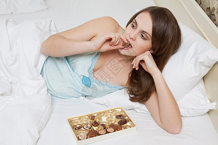 女人在床上吃巧克力图片素材