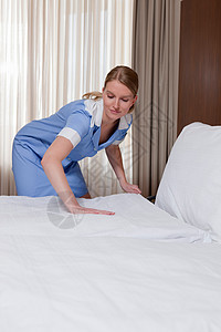 客房服务员在酒店房间里整理床铺图片