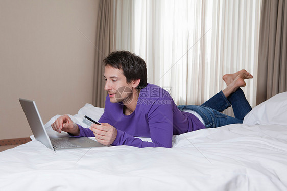 带笔记本的酒店床上的男人图片