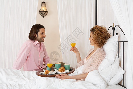 年轻夫妇在床上共享早餐图片