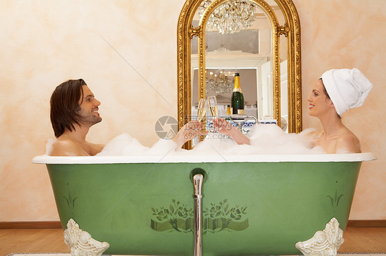 坐在浴缸里祝酒的年轻夫妇图片