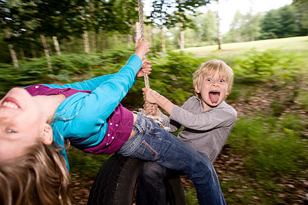 男孩和女孩在轮胎秋千上摇摆图片