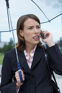 愤怒的女商人在雨伞下图片