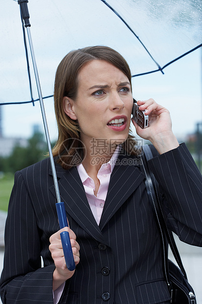 愤怒的女商人在雨伞下图片