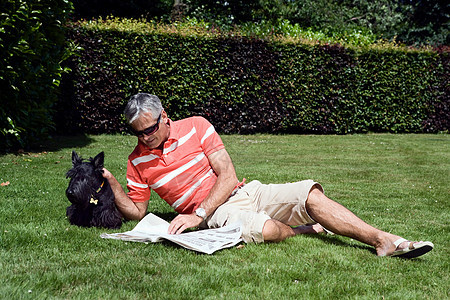 成熟的男人躺在草地上看书图片