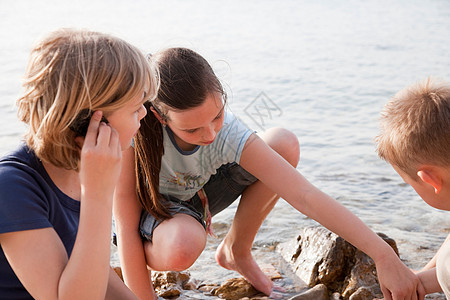 孩子们在海滩上听贝壳图片