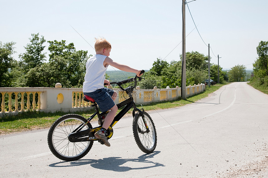 在乡村公路上骑自行车的男孩图片