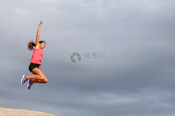 在巨石上跳跃的女人图片