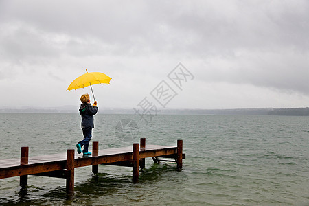 男孩拿着雨伞在木码头上图片