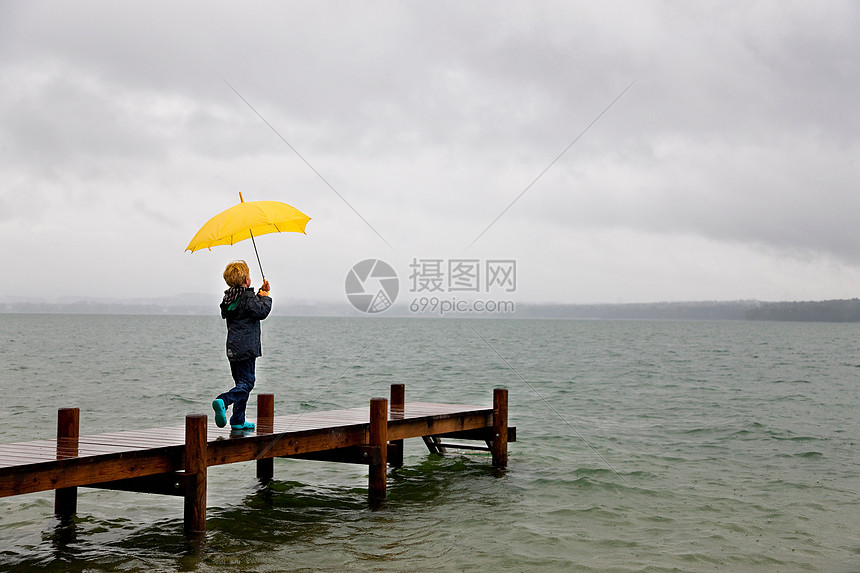 男孩拿着雨伞在木码头上图片