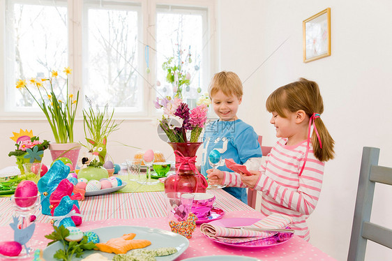 男孩和女孩在复活节餐桌上玩耍图片