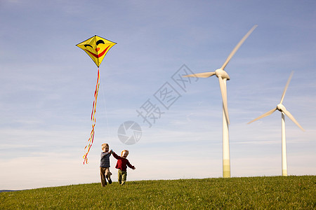 两个男孩在风力涡轮机上放风筝图片