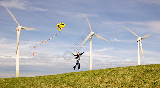 在风车下拿着风筝跳的人图片