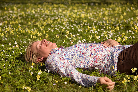 男人躺在开着花的草地上图片