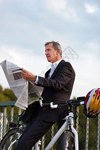 坐在自行车上看报的商务男性图片