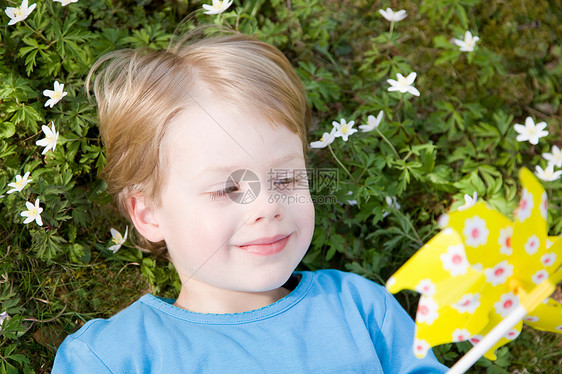男孩拿着玩具风车躺在草地上图片